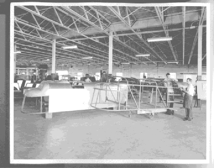 two men moving a train engined shaped frame in place to have a skin placed over it which would be used to surround a Ford 611 tractor with a train-like body